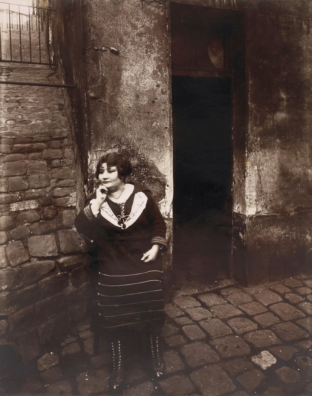 La Villette. Rue Asselin, prostituoitu odottaa ovensa edessä tekijältä Eugène Atget