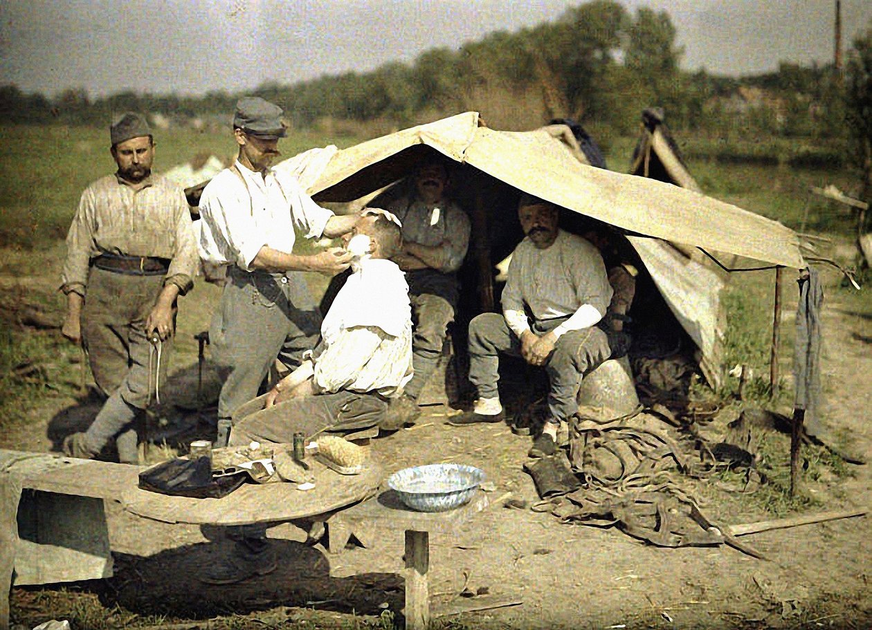 Parturi ajelee sotilasta ranskalaisella sotilasleirillä, Soissons, Aisne, Ranska, 1917 (autokromi) tekijältä Fernand Cuville