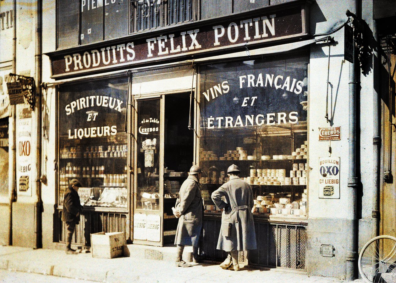 Kaksi ranskalaista sotilasta ja poika Felix Potinin viinakaupan edessä torilla, Reims, Marne, Ranska, 1917 (autokromi) tekijältä Fernand Cuville