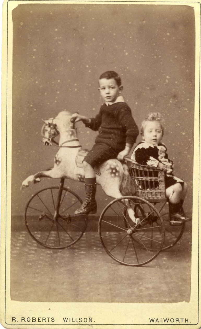 Nuori poika keinuhevosella, takana nuori tyttö pajuvaunuissa, 1880-luku (albumiprintti) tekijältä R. Roberts Willson